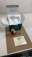 Figurine, certificate, pin, and open box with insert displayed