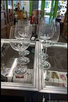 Five clear stemmed wine glasses on display case