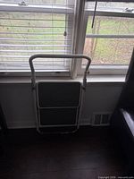 Stool folded flat against wall below window