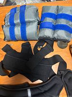 Pair of grey ankle weights with blue straps plus portions of black weighted vest