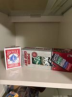 Sealed Bicycle deck beside boxed poker chip set on shelf