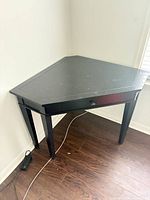 Full view of black corner table against wall