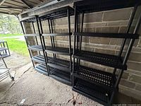 Two assembled black plastic shelving units against wall