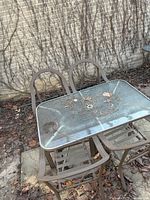 Table with glass top and two of the chairs, showing debris and glass damage