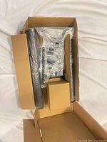 Opened box showing ceiling pole, mounting plate, sealed hardware packs and small interior box