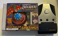 Front view of boxed tin spaceship beside tricorder