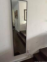 Full-length rectangular mirror mounted on wall near staircase