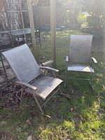 Both gray metal rocking⁄glider chairs on lawn