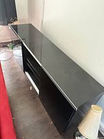 Overall view of black media cabinet showing glass top and long low form