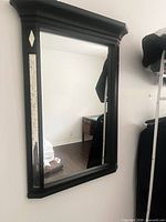 Full view of black wood wall mirror hanging on wall