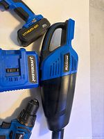 Cordless handheld vacuum, battery pack, portion of drill and charger visible