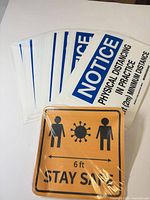 Stack of white NOTICE distancing stickers and orange STAY SAFE sticker pack