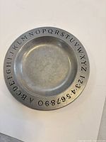 Front view showing alphabet and number border on pewter plate