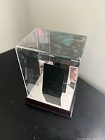 Front view assembled display case showing acrylic cover over mirrored wood base and black riser
