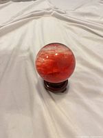 red glass sphere on wooden stand