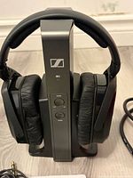 Front view of headphones on base showing controls and logo