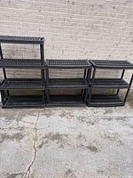 All three black plastic 3-tier shelving units lined against a wall