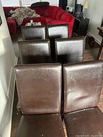 Front view of all six dark brown faux leather Parsons chairs lined up