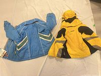 Two Spyder youth jackets, yellow/black and blue/green, front view
