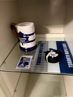Mug, trading card, cutting board and puck grouped on shelf