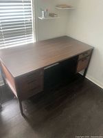 Front view of walnut veneer desk showing overall form and drawers