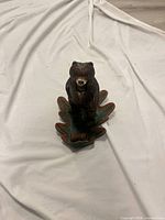 Front view of cast iron bear figurine on leaf base