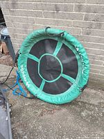 Front view of VivaActive saucer swing showing green padded rim, black mesh center and blue ropes