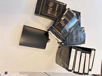 Group of boxed and unboxed black hip flasks on table