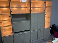 Full view of four-section cream display wall unit with glass doors, shelves and lighting