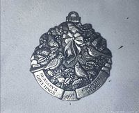 Front view of pewter wreath ornament with inscription visible