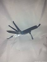 Multi-tool open showing knife blade, saw blade, fish scaler and Phillips driver