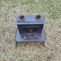 front view of cast iron furnace showing twin burner holes, loading door and ash drawer