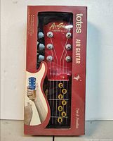 Front of boxed Totes Air Guitar showing product through window