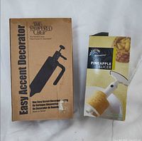 Pampered Chef decorator box and Vacu Vin pineapple slicer box side by side