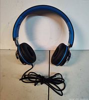 Front view of blue/black Ailihen wired headphones with cable coiled