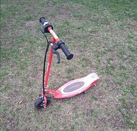 Side view of red Razor electric scooter on grass