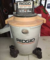Front view showing Ridgid branding, canister body, attachment pieces