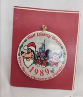 Front view of porcelain ornament showing characters, text and hanging cord on red card