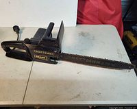 Left side view of entire chainsaw showing bar, housing, power cord