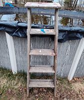 Front view of full wooden ladder showing five treads and wear