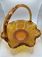 Overhead angled view of amber pressed glass basket showing ruffled rim and handle