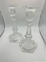 Two clear glass candlestick holders standing upright