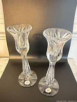 Front view of both crystal candlesticks on dark backdrop showing cut design and height