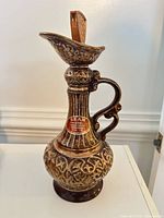 Full view of ornate brown and gold Jim Beam ceramic decanter with stopper