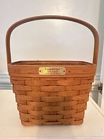 Front view showing weave pattern, handle, and brass nameplate