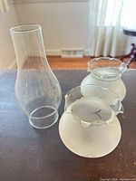 clear glass chimney and two frosted globes side by side
