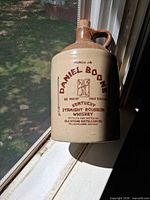 Front view of stoneware jug on windowsill showing printed label and two-tone glaze