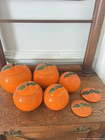 five orange ceramic canisters with two spare lids