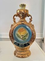 Front view of gold ceramic Jim Beam decanter with stopper