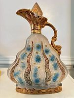 Full view of ornate ceramic decanter showing shape, stopper, floral and gold decoration